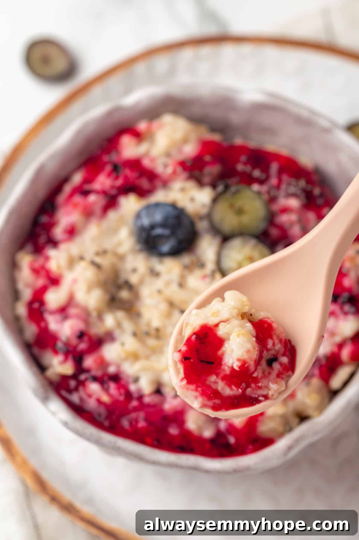 Spoonful of creamy baby oatmeal topped with vibrant berry jam, ready to be enjoyed.