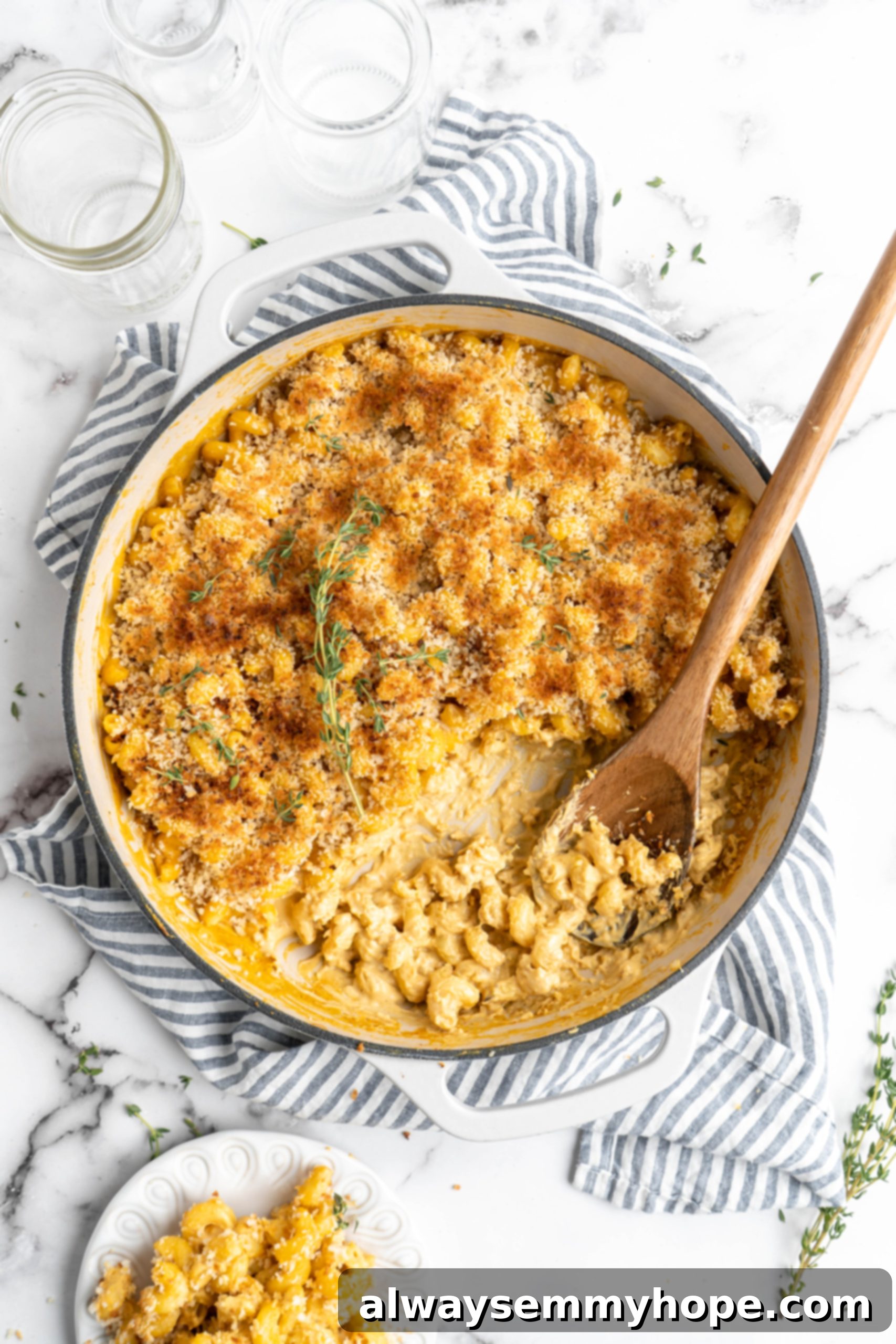 Baked vegan mac and cheese in skillet with wooden spoon, using nutritional yeast as a dairy substitute