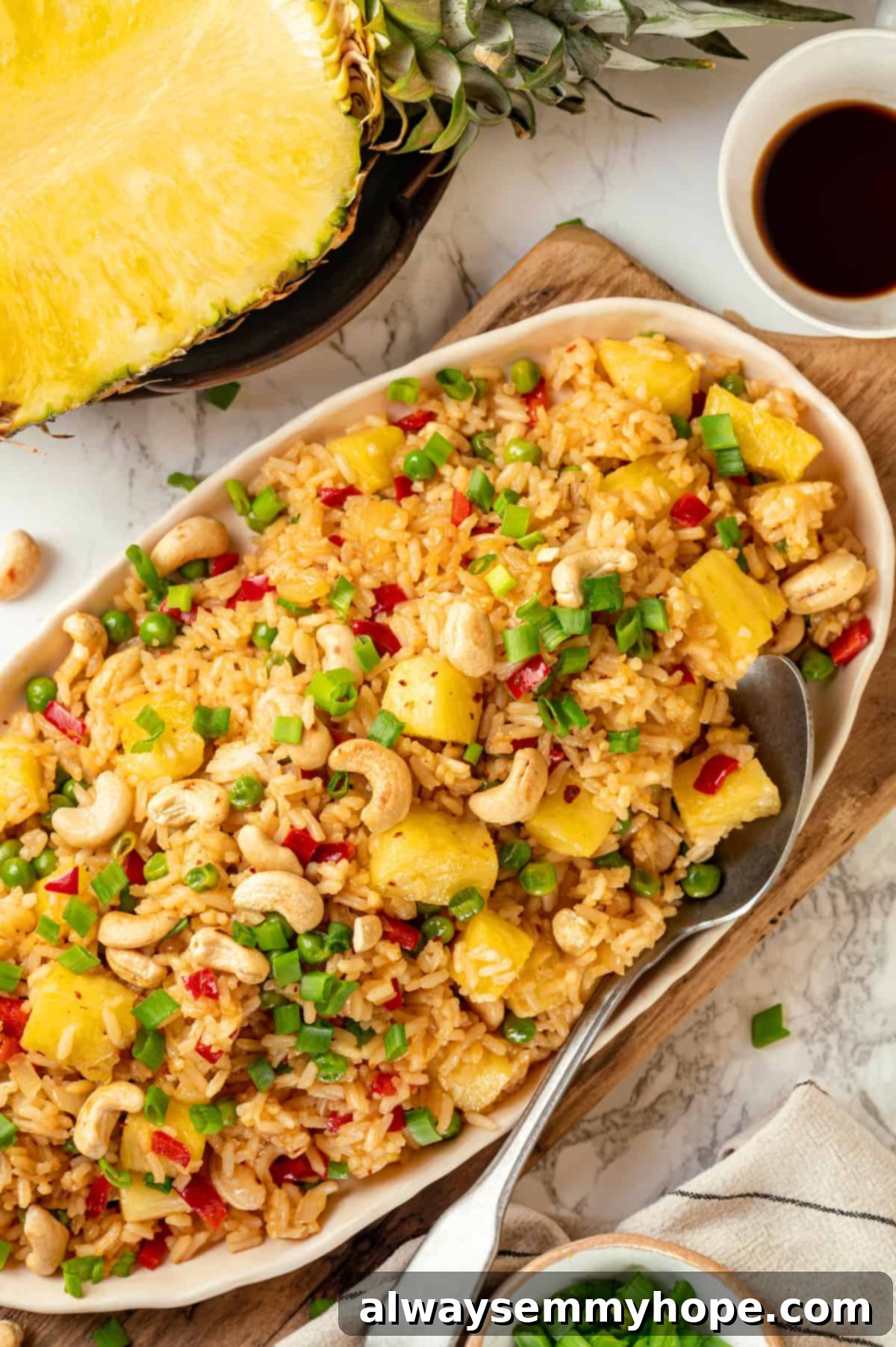 Overhead view of pineapple fried rice on platter with serving spoon