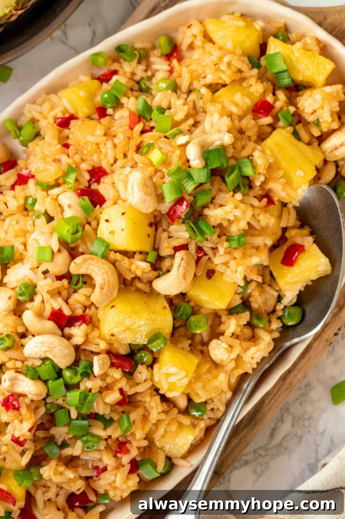 This easy homemade pineapple fried rice recipe gives you that perfect perfect balance of sweet and salty flavour in every bite. Ready in minutes! Platter of pineapple fried rice with serving spoon