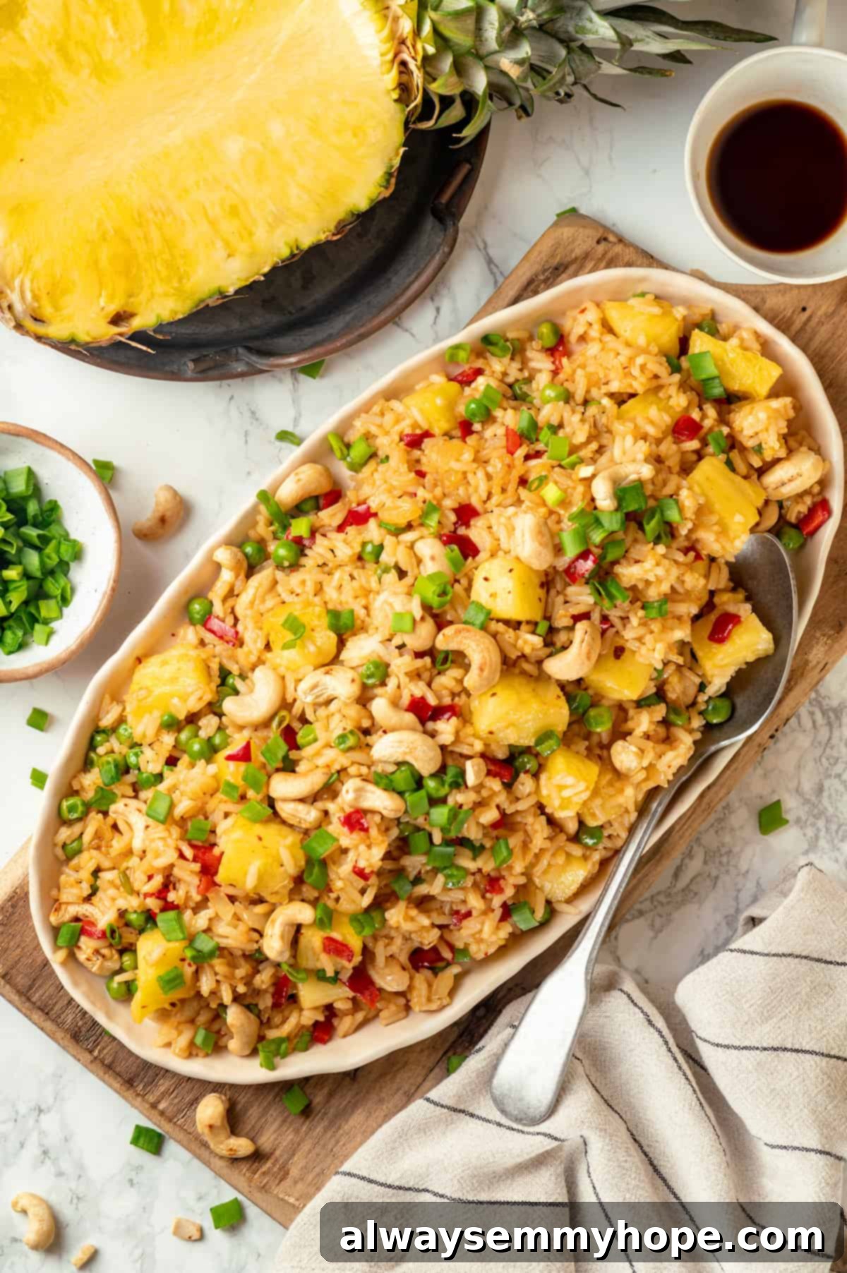 This easy homemade pineapple fried rice recipe gives you that perfect balance of sweet and salty flavour in every bite. Ready in minutes! Overhead view of pineapple fried rice on platter with large spoon