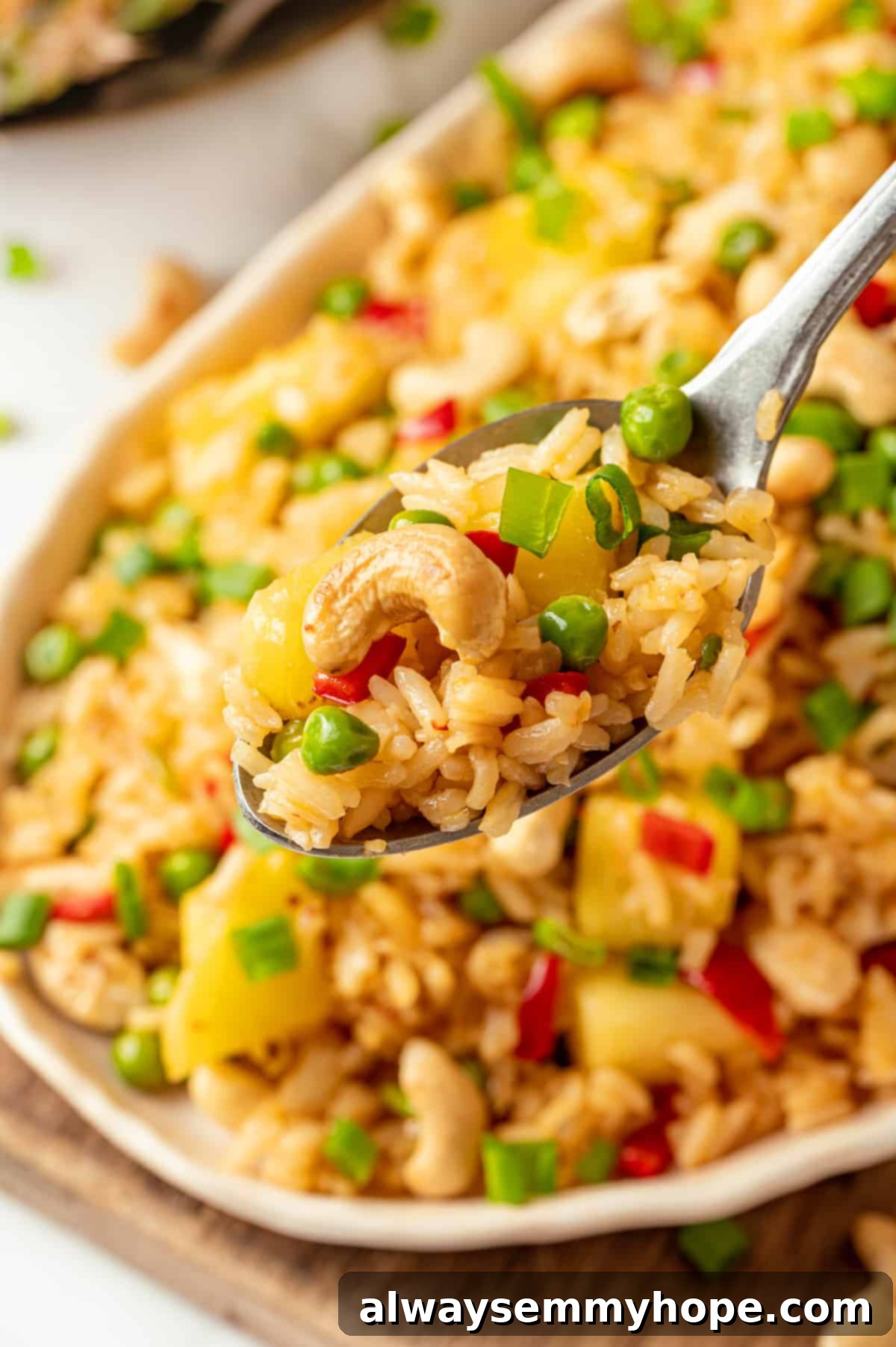 Spoonful of pineapple fried rice held over platter of rice