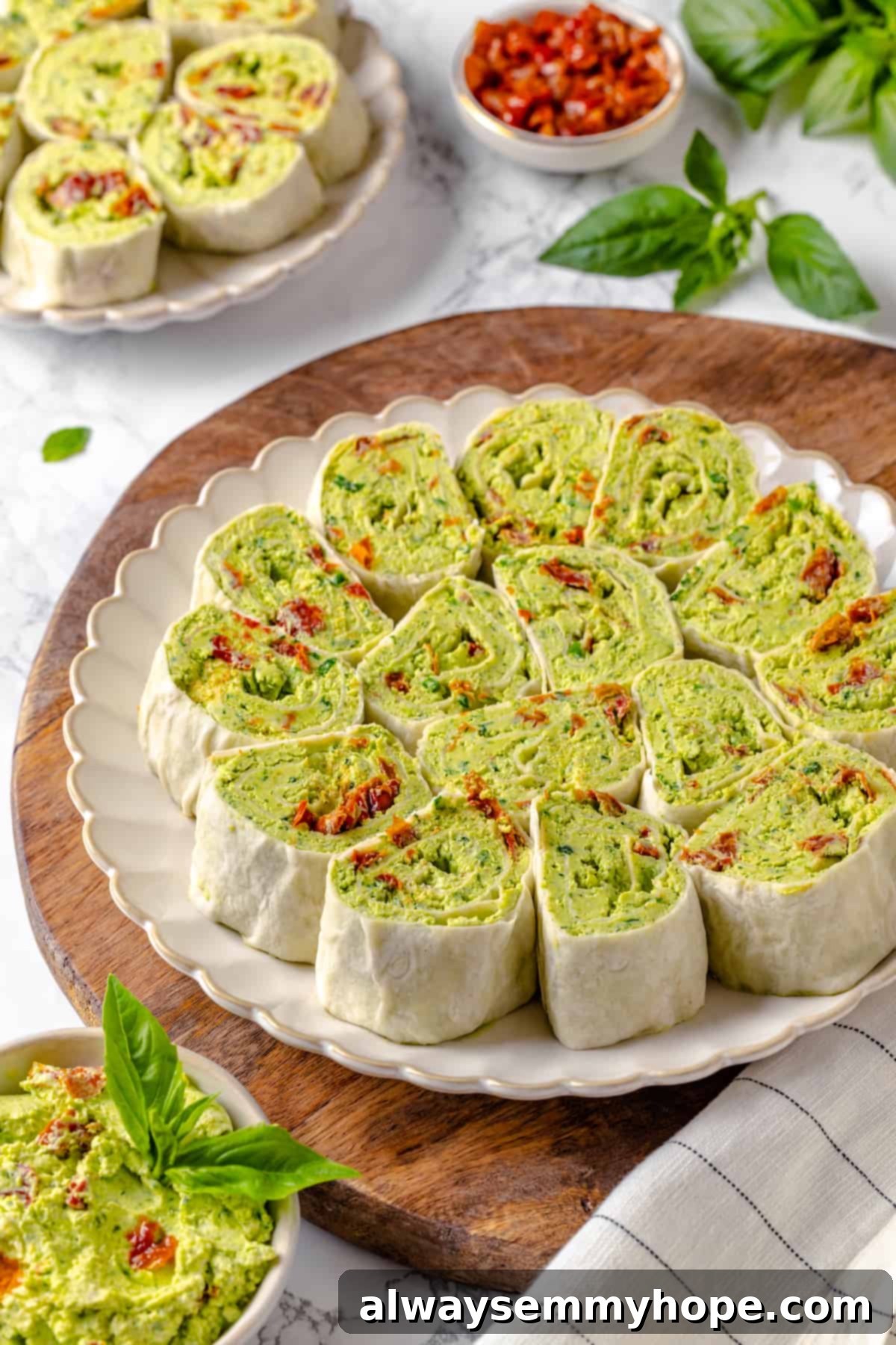 With cream cheese, pesto, Parmesan, and sun-dried tomatoes, these easy pinwheel sandwiches are full of flavour. Great for a party or lunch! Plate of pesto pinwheel sandwiches with sun-dried tomatoes