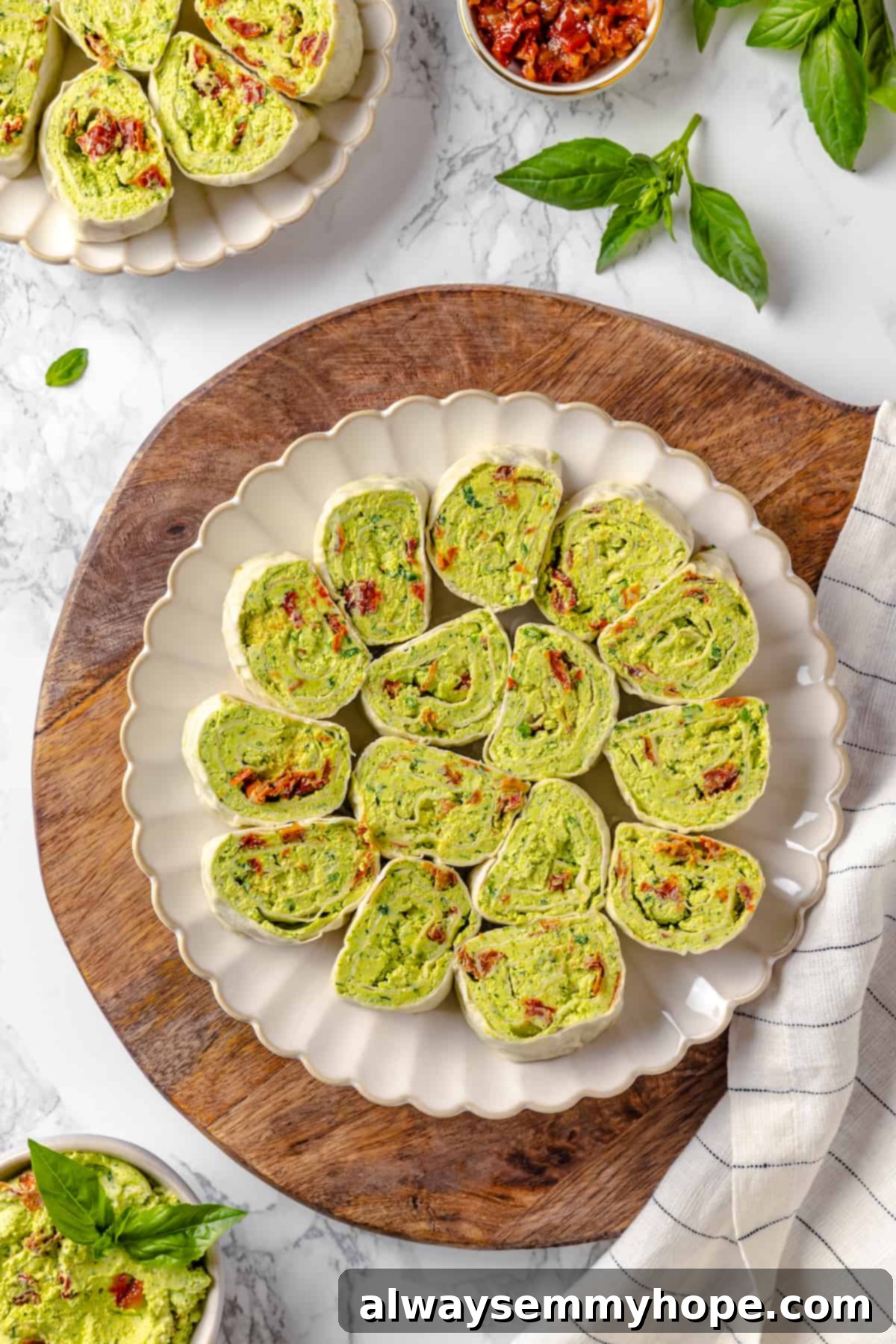 With cream cheese, pesto, Parmesan, and sun-dried tomatoes, these easy pinwheel sandwiches are full of flavour. Great for a party or lunch! Overhead view of vegan tortilla roll-ups with pesto and cream cheese