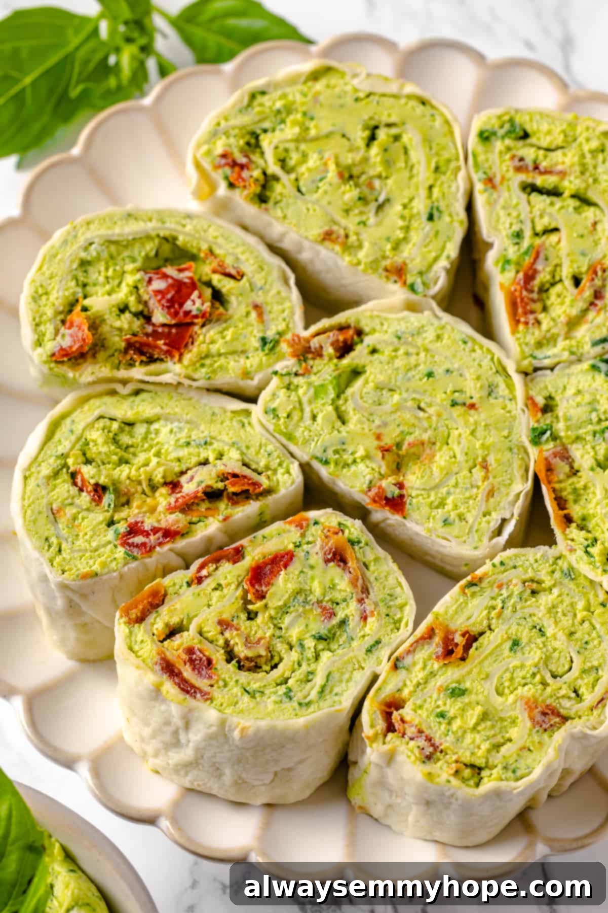 With cream cheese, pesto, Parmesan, and sun-dried tomatoes, these easy pinwheel sandwiches are full of flavour. Great for a party or lunch! Overhead view of pesto pinwheel sandwiches on plate