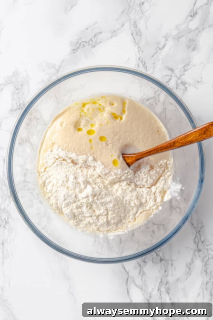 This soft pretzel recipe is fun to make and the results are outstanding—chewy, buttery, and perfect to serve with your fave dipping sauce! Overhead view of flour added to bowl of pretzel dough