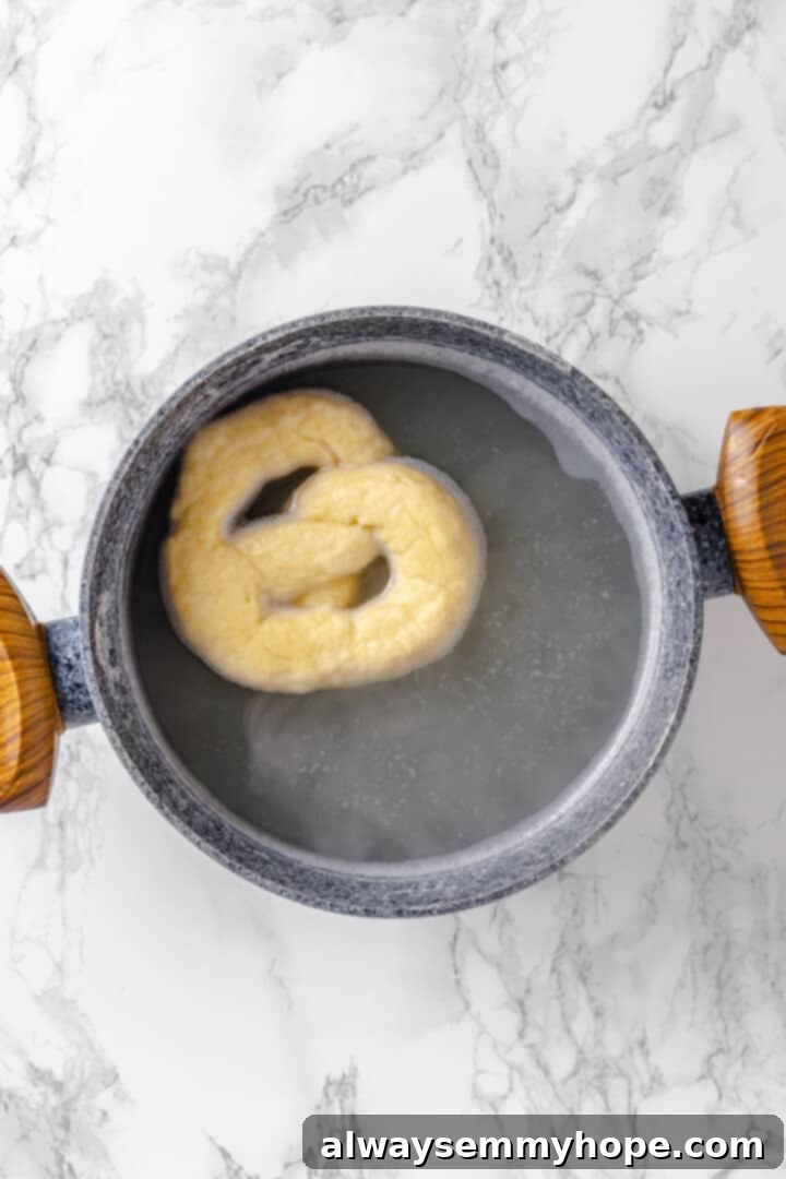 This soft pretzel recipe is fun to make and the results are outstanding—chewy, buttery, and perfect to serve with your fave dipping sauce! Overhead view of pretzel in boiling water