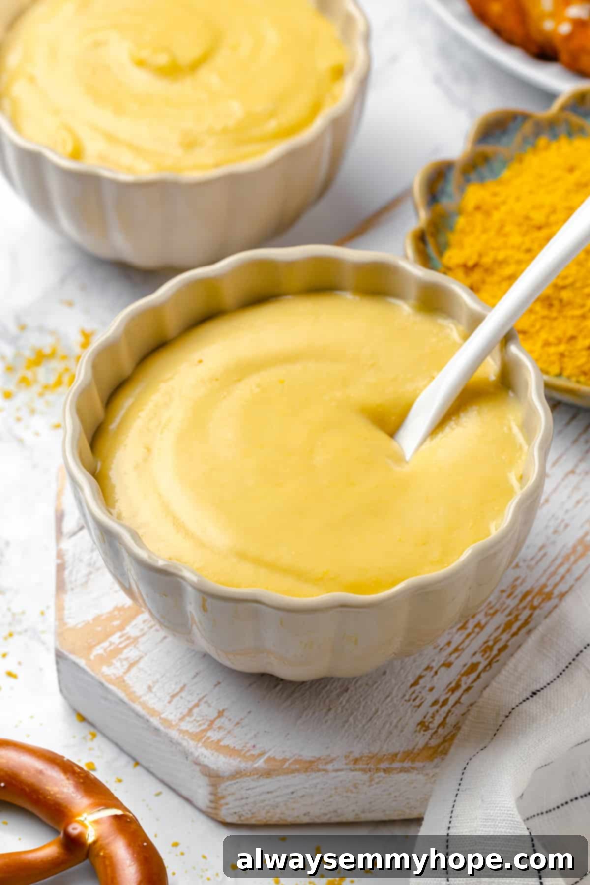 Two bowls of vegan pretzel dip, showcasing its creamy texture