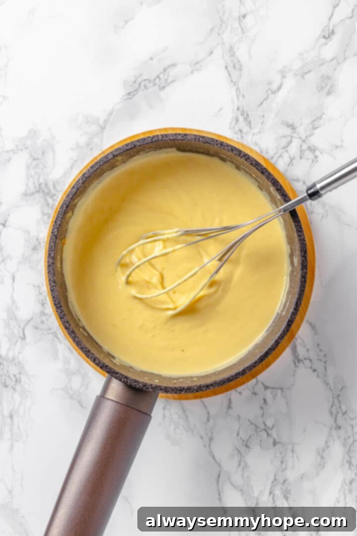 A whisk vigorously mixing the pretzel dip ingredients in a pan