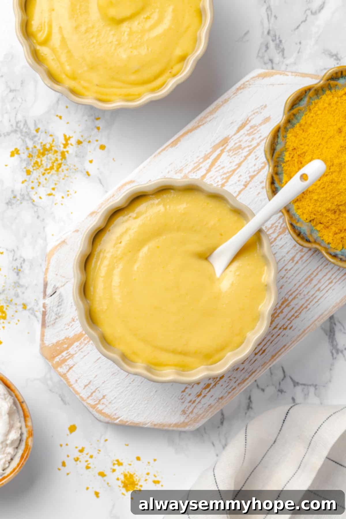 Overhead view of two bowls filled with golden vegan pretzel dip, garnished slightly