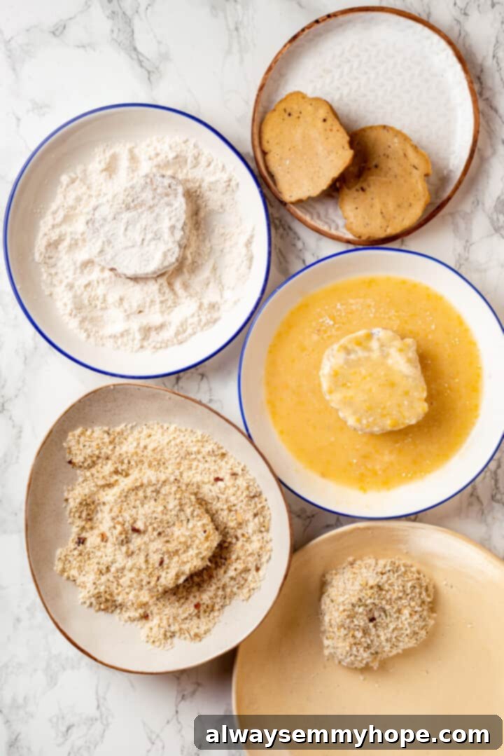 Overhead view of a perfectly organized dredging station with three bowls for flour, egg substitute, and breadcrumbs, ready for the vegan chicken cutlets.