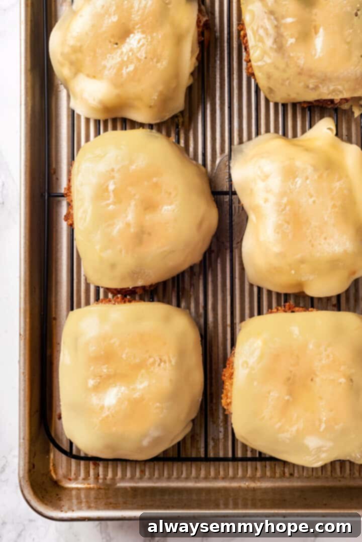 Overhead view of vegan provolone slices melting and bubbling on top of crispy vegan chicken cutlets under a broiler, creating gooey perfection for the parm sandwich.