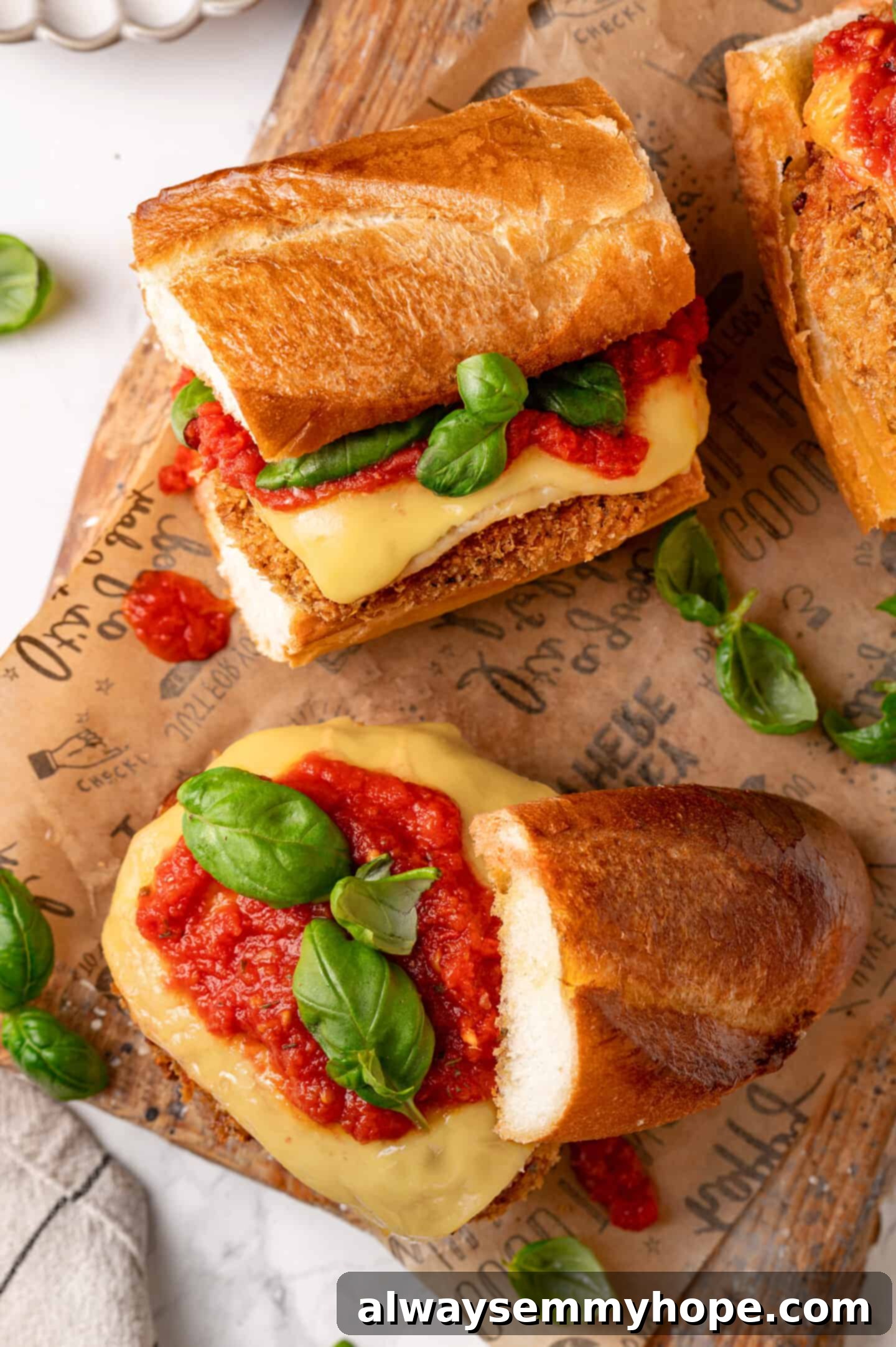 Overhead view of several perfectly assembled vegan chicken parm sandwiches, ready to be served, on a dark background.