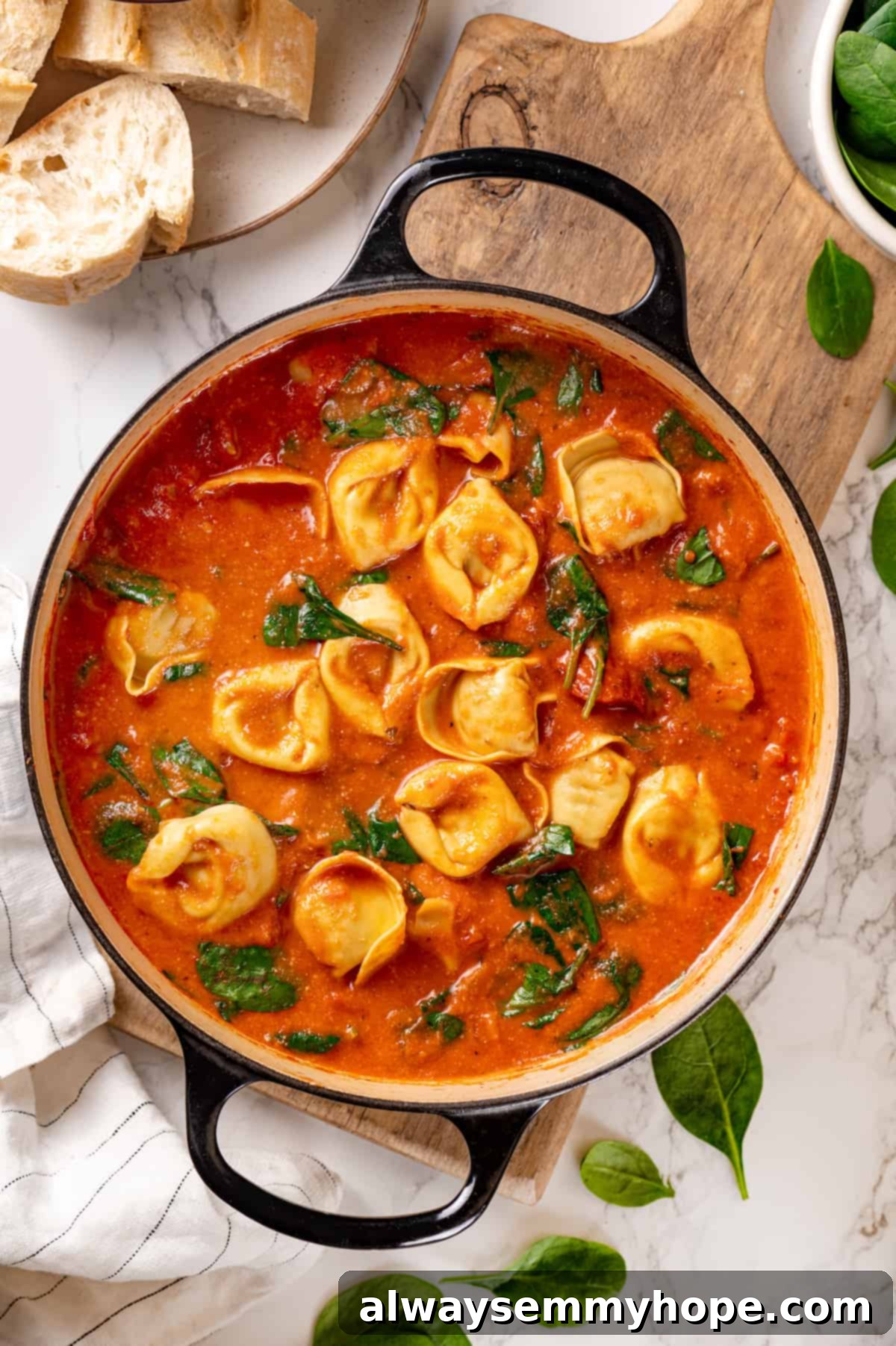 This easy tomato tortellini soup recipe is comfort food in a bowl. You’ll love the creamy tomato broth but the tortellini is the best part! Overhead view of tomato tortellini soup in pot