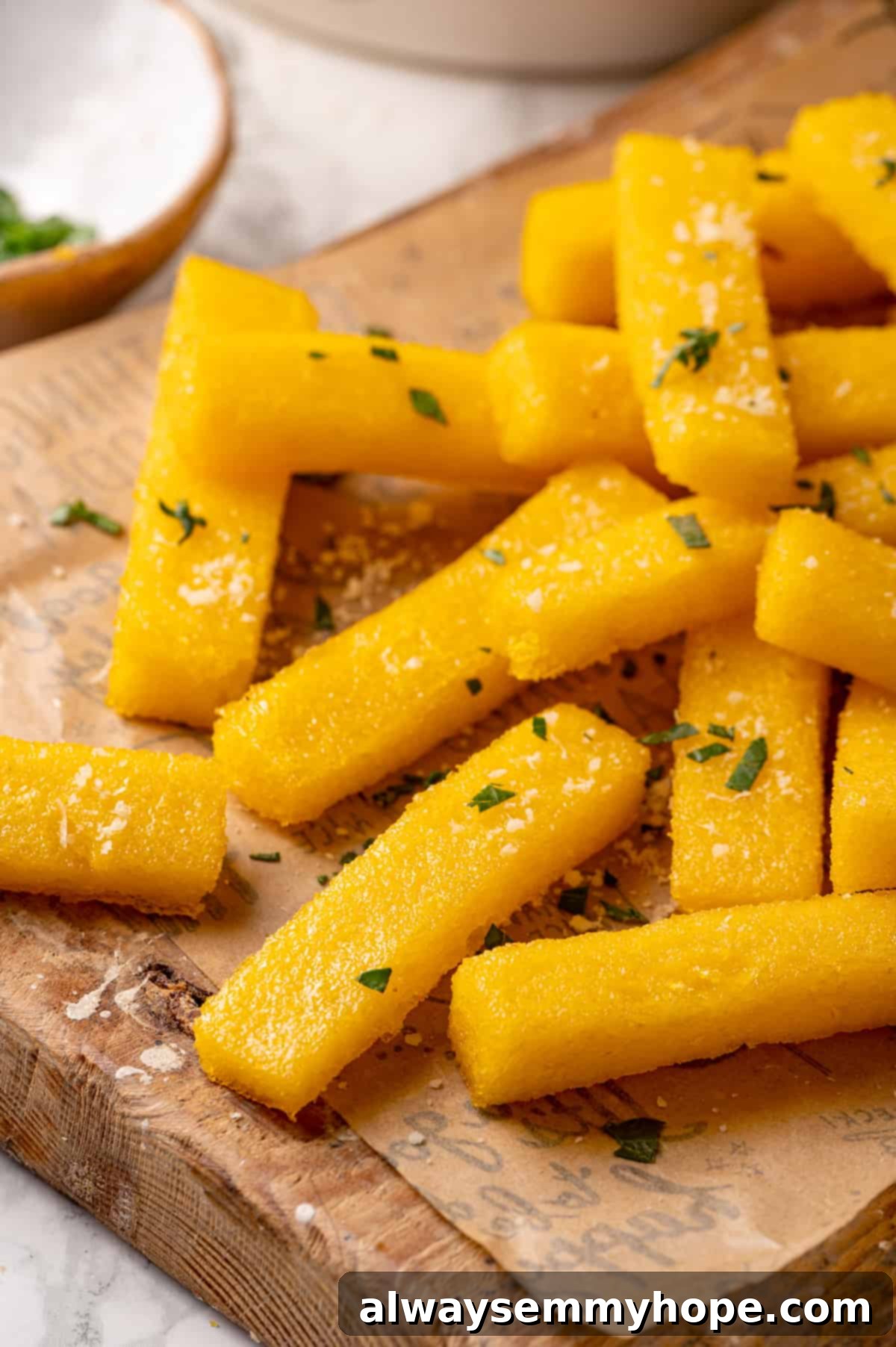 A plate of golden and perfectly crispy fried polenta Close-up of golden, crispy fried polenta sticks arranged artfully on a parchment-lined board