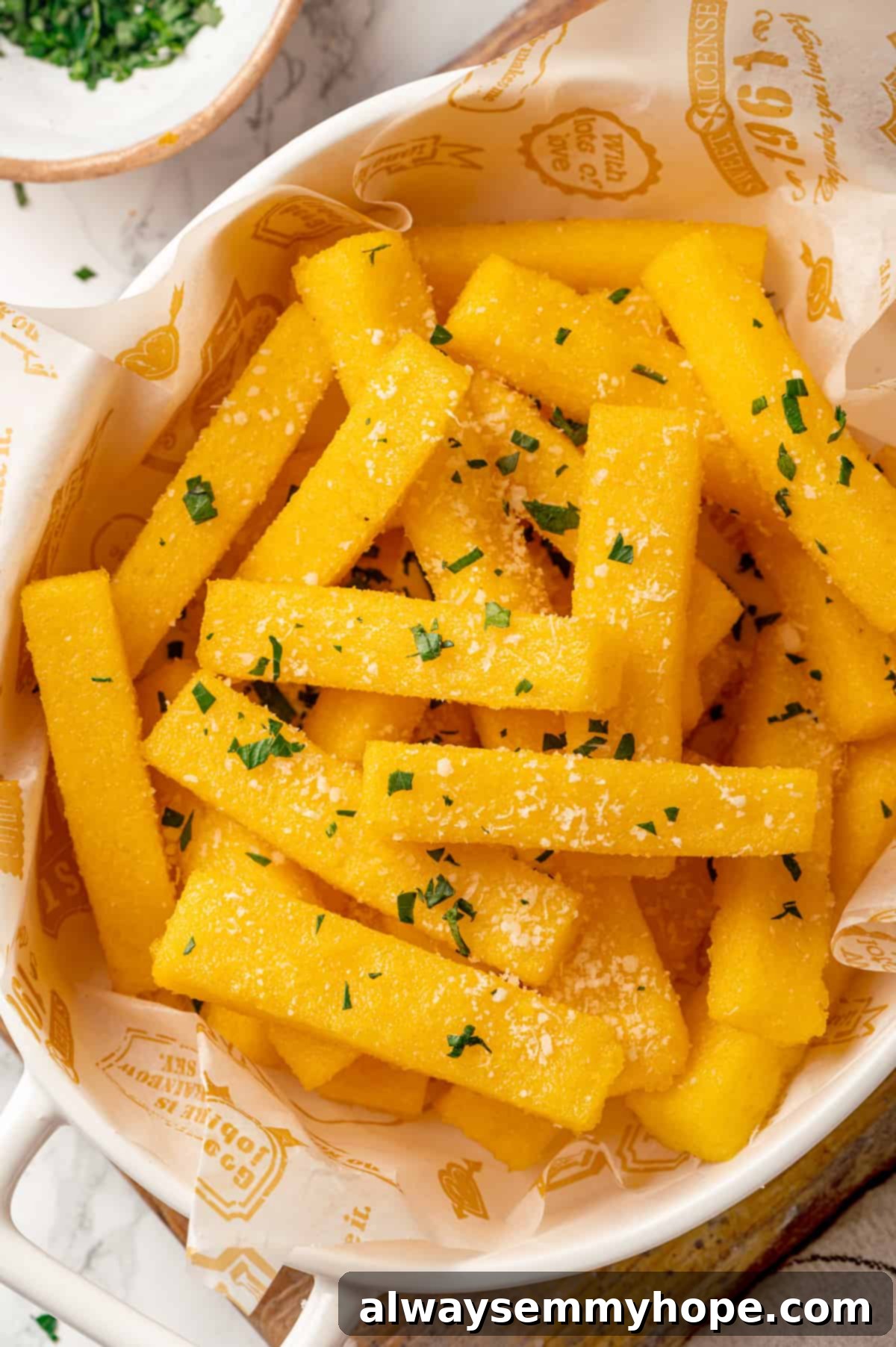 Delicious fried polenta served with vegan parmesan and fresh herbs Overhead view of crispy fried polenta topped with parmesan and parsley, showcasing its vibrant appeal