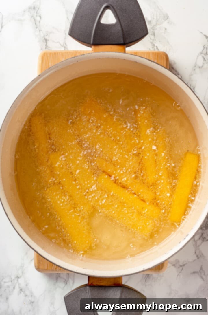 Polenta strips frying in hot oil until golden and crispy Overhead view of polenta fries being deep fried to a golden crisp in hot oil