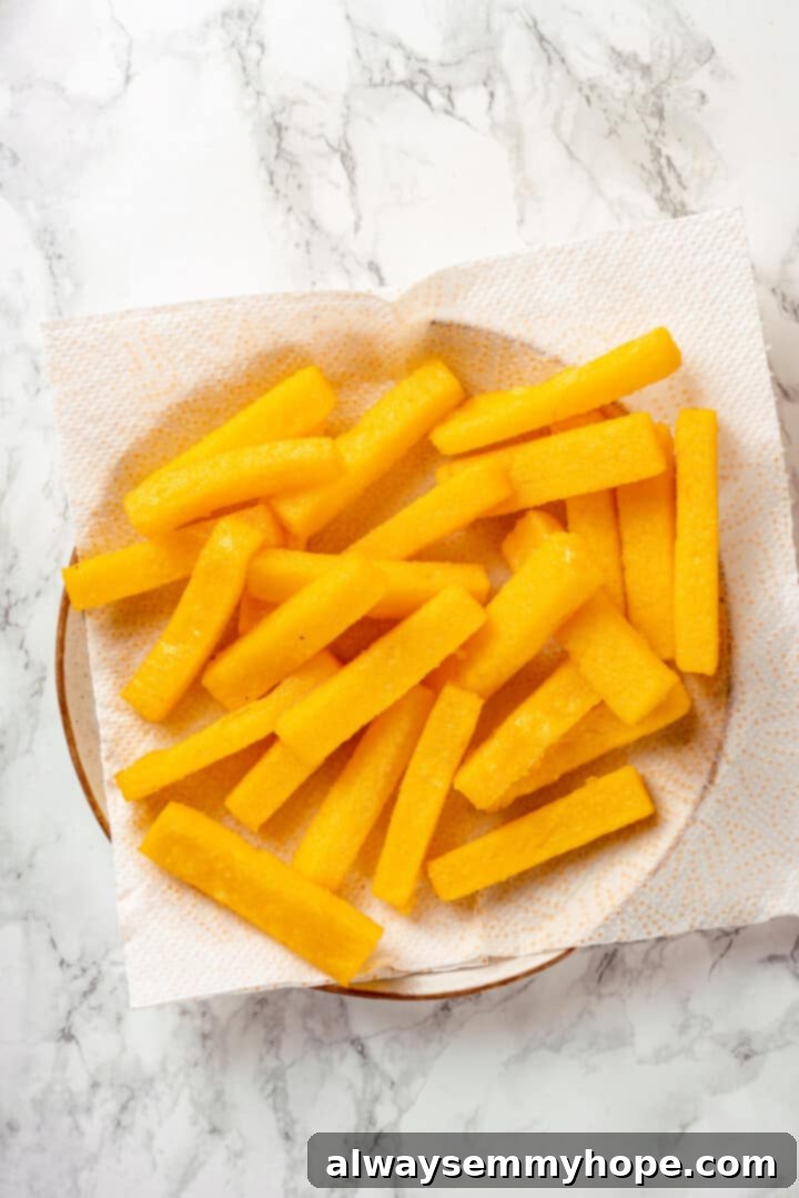 Draining excess oil from fried polenta on paper towels Overhead view of crispy fried polenta draining excess oil on a paper towel-lined plate