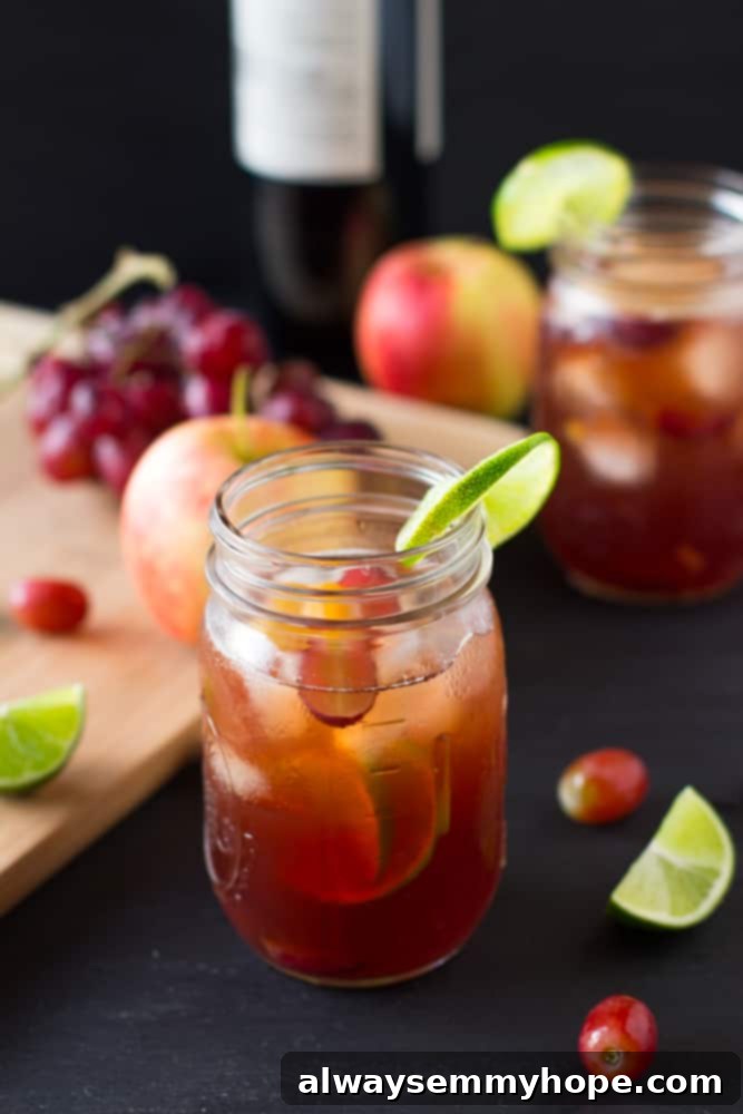Rosé Sangria in a rustic mason jar, garnished with fresh lime, on a dark table, highlighting its vibrant pink color and refreshing appeal.