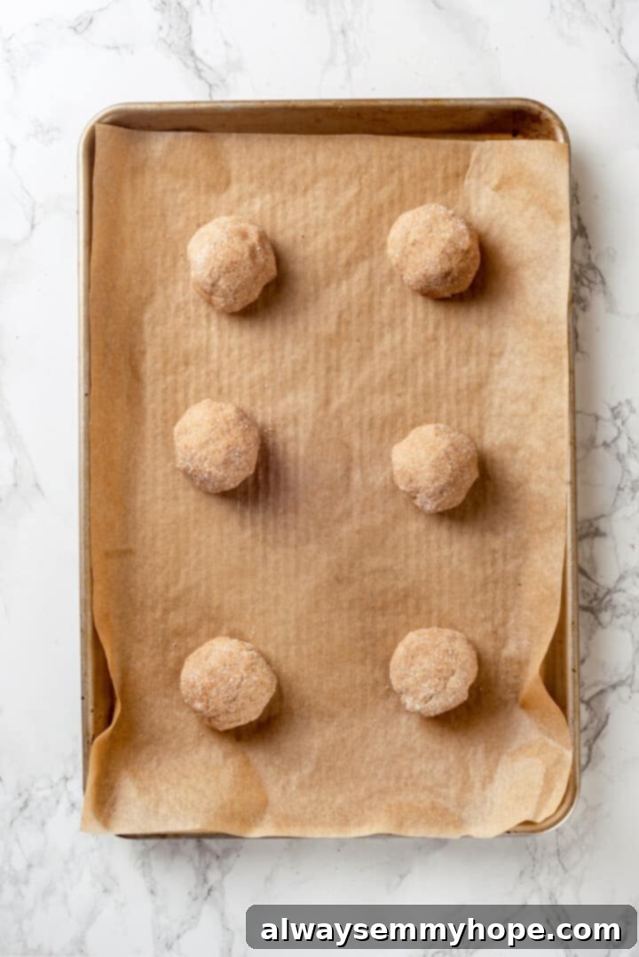 Overhead view of perfectly portioned chai sugar cookie dough balls on a lined sheet pan, ready for baking