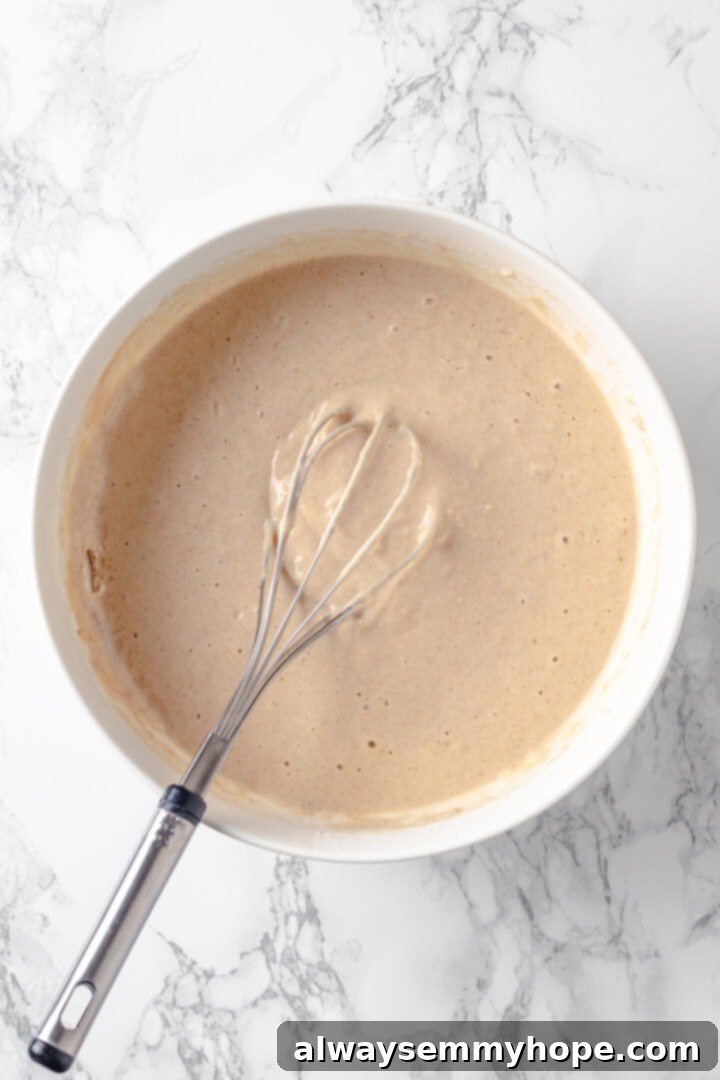 Overhead view of silver dollar pancake batter in bowl with whisk