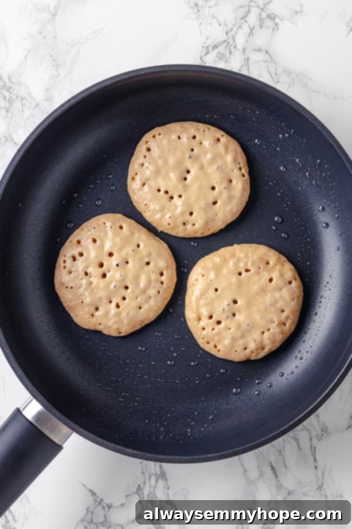Overhead view of silver dollar pancakes in skillet after flipping