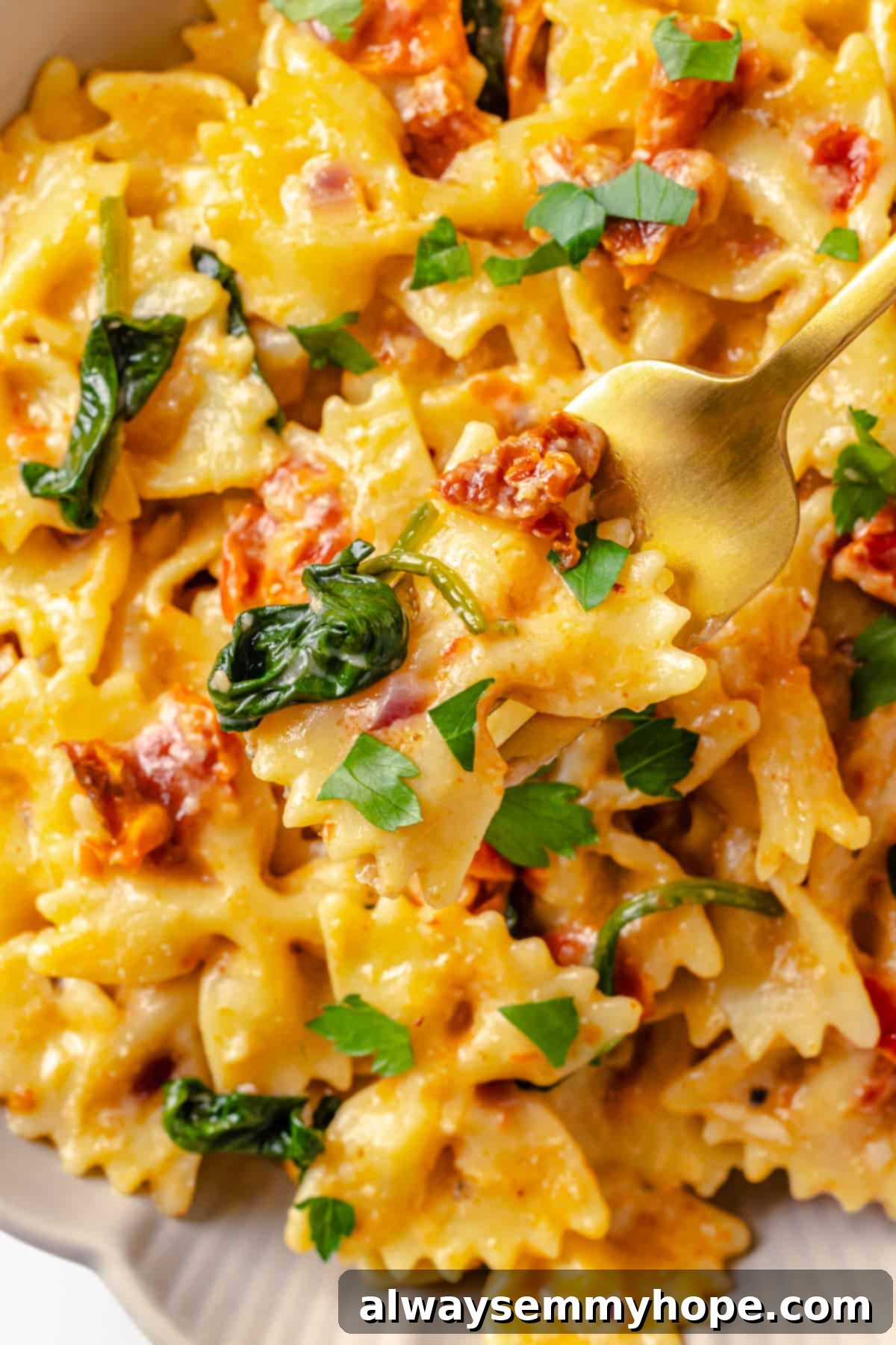 Creamy sun-dried tomato pasta, a healthy and delicious vegan dinner. Overhead view of creamy vegan sun-dried tomato pasta with wilted spinach, garnished with fresh herbs, in a wide, shallow bowl.