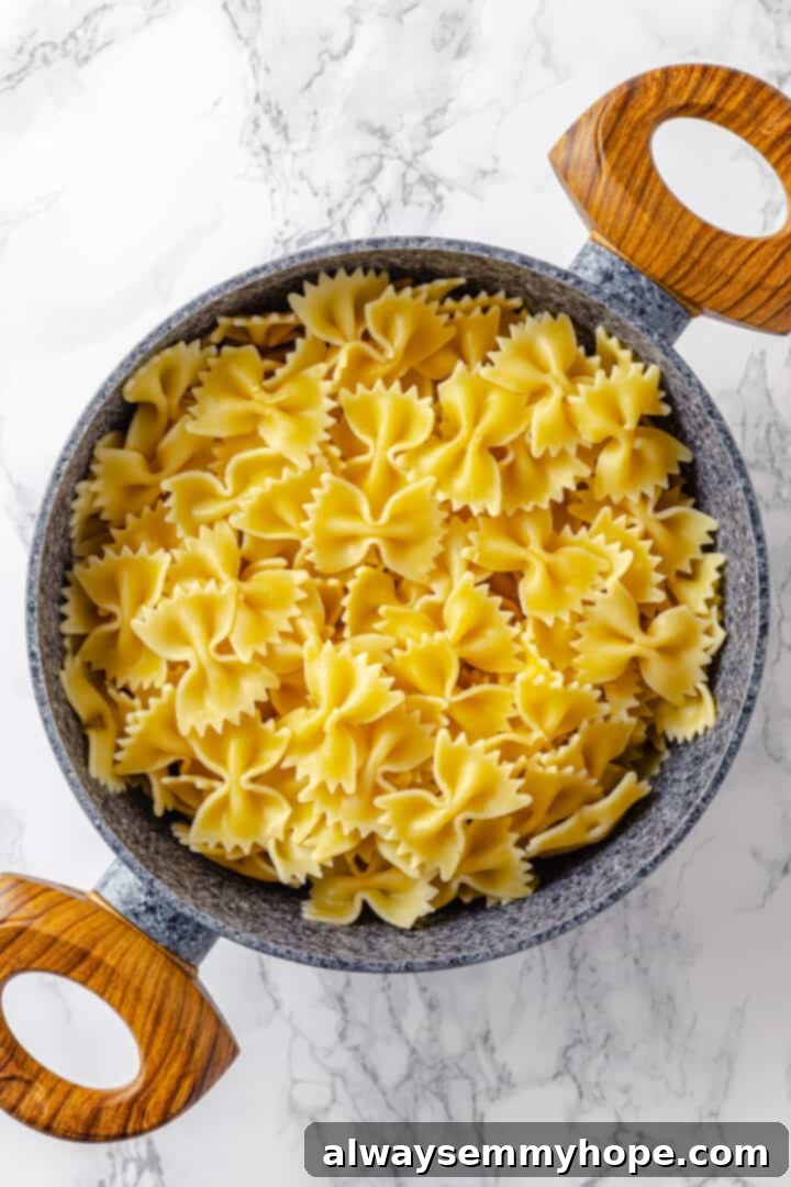 Cooked al dente bowtie pasta, drained and ready for the creamy sauce. Cooked farfalle pasta in colander, steam rising gently.