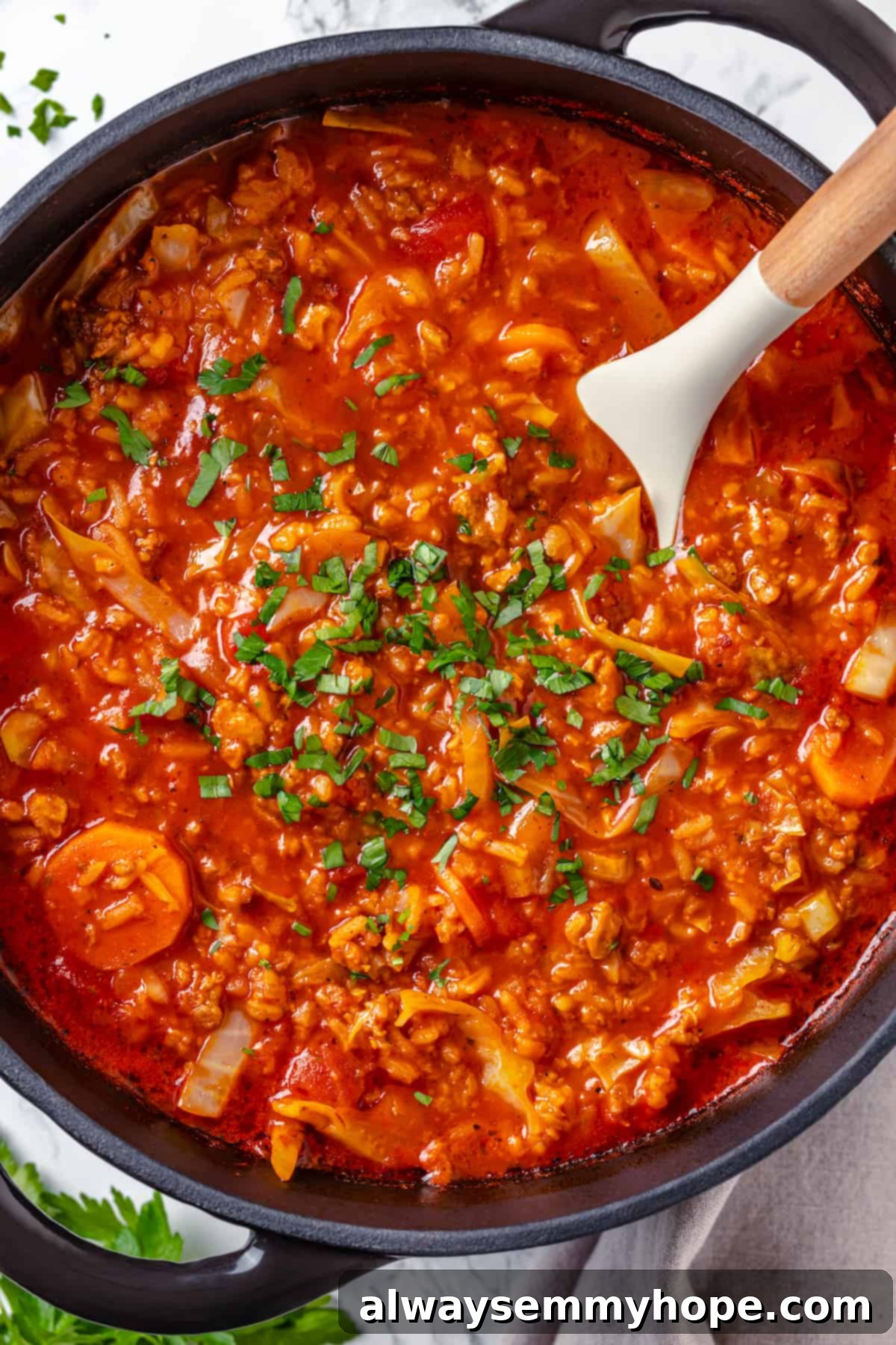 Satisfying cabbage roll soup is a filling meal in a bowl! Skip all the work and enjoy your cabbage rolls in the form of a hearty soup recipe. A wooden spoon gently stirring a rich, steaming pot of vegan cabbage roll soup, highlighting its thick texture and ingredients.
