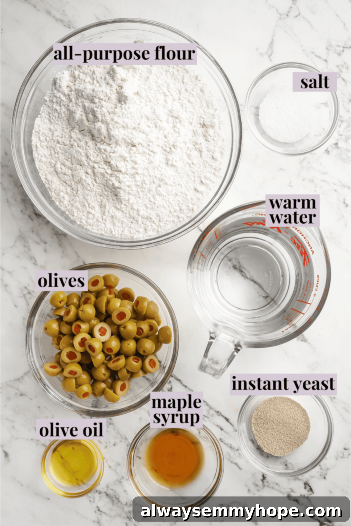 This crusty no-knead olive bread recipe is perfect for beginning bakers, but seasoned pros will love it too. Easy and delicious! Overhead view of ingredients for olive bread, neatly arranged with labels for clarity