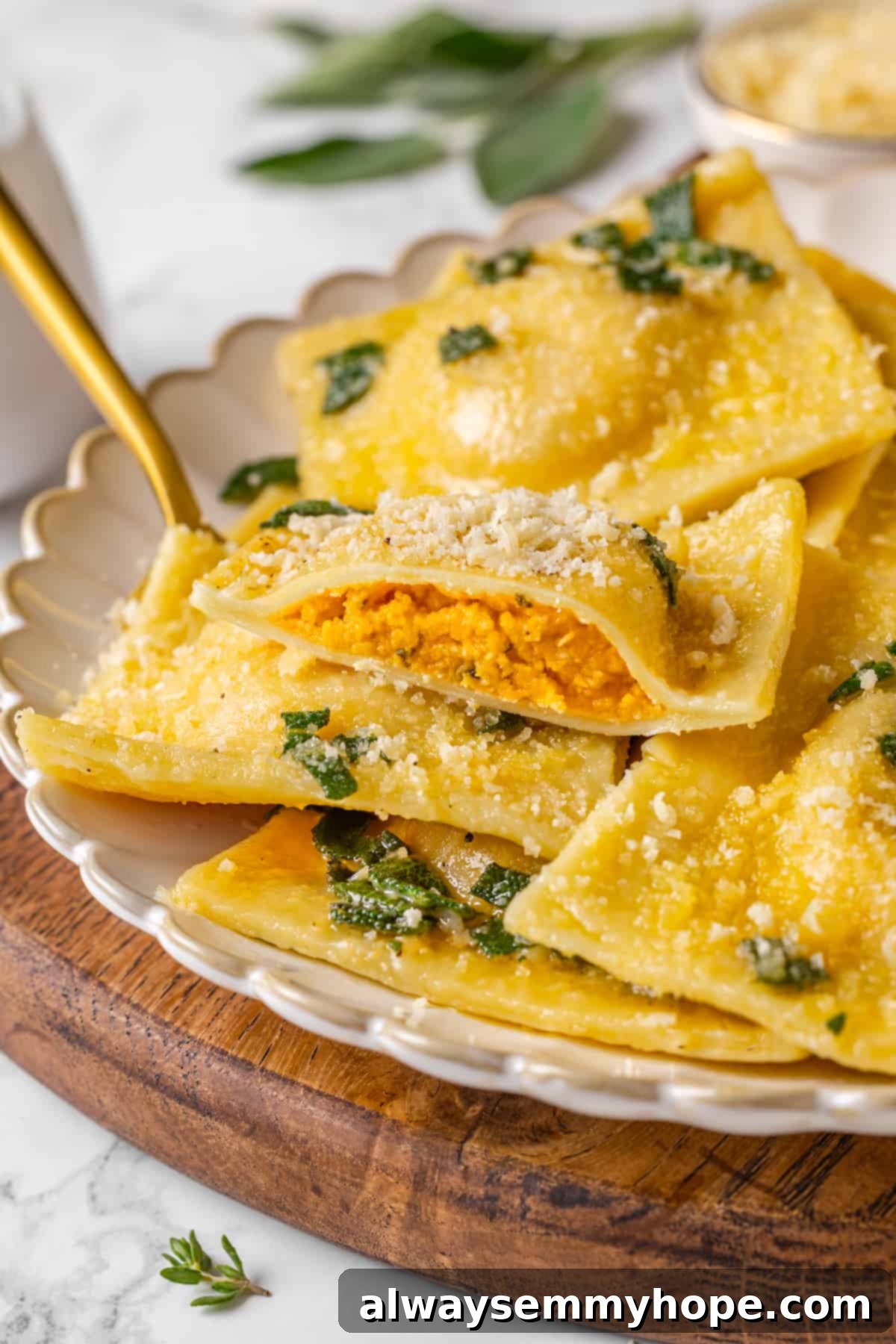 Butternut squash ravioli is fun to make at home and the results are delicious. Tender pasta pockets filled with creamy, caramelized squash! Butternut squash ravioli on plate with one ravioli sliced to show inside