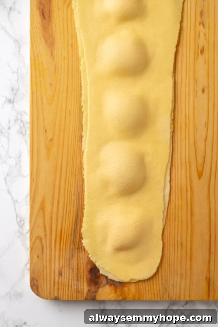 Butternut squash ravioli is fun to make at home and the results are delicious. Tender pasta pockets filled with creamy, caramelized squash! Ravioli on board before cutting