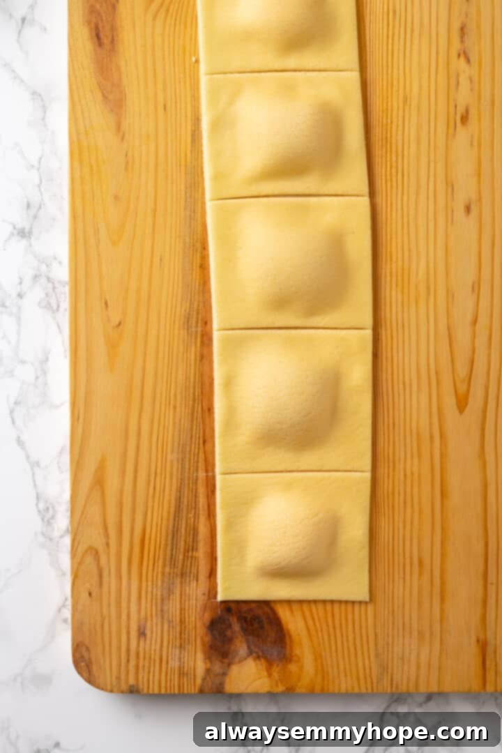 Butternut squash ravioli is fun to make at home and the results are delicious. Tender pasta pockets filled with creamy, caramelized squash! Cut ravioli on wooden board