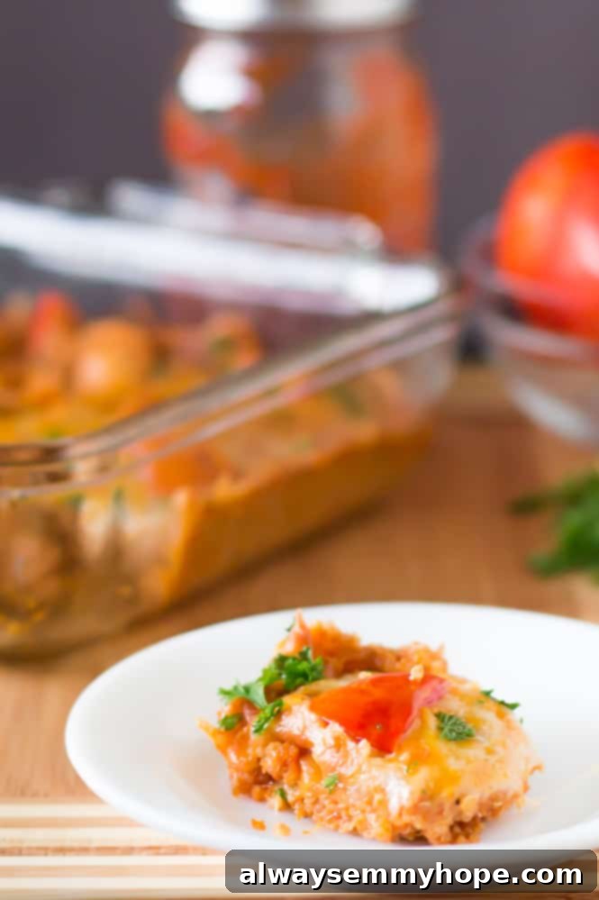 A slice of golden-brown cheesy quinoa casserole with roasted tomatoes, served on a white plate, ready to be enjoyed as a quick and healthy vegan meal.