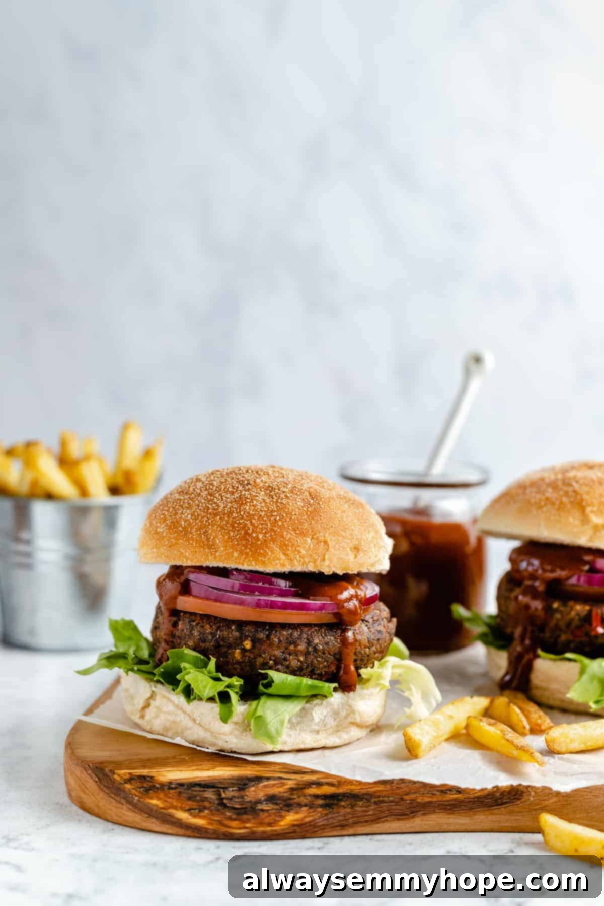 Black bean burgers are made with cooked quinoa, sautéed onions, and smoky strawberry BBQ sauce! Veggie burgers have never tasted this good! Veggie burger with toppings and a bun.