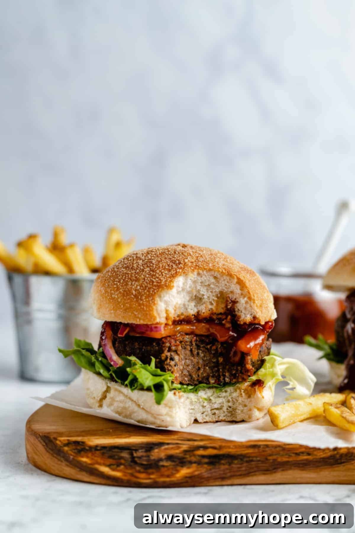 Black bean burgers are made with cooked quinoa, sautéed onions, and smoky strawberry BBQ sauce! Veggie burgers have never tasted this good! A veggie burger with a bite taken out of it.