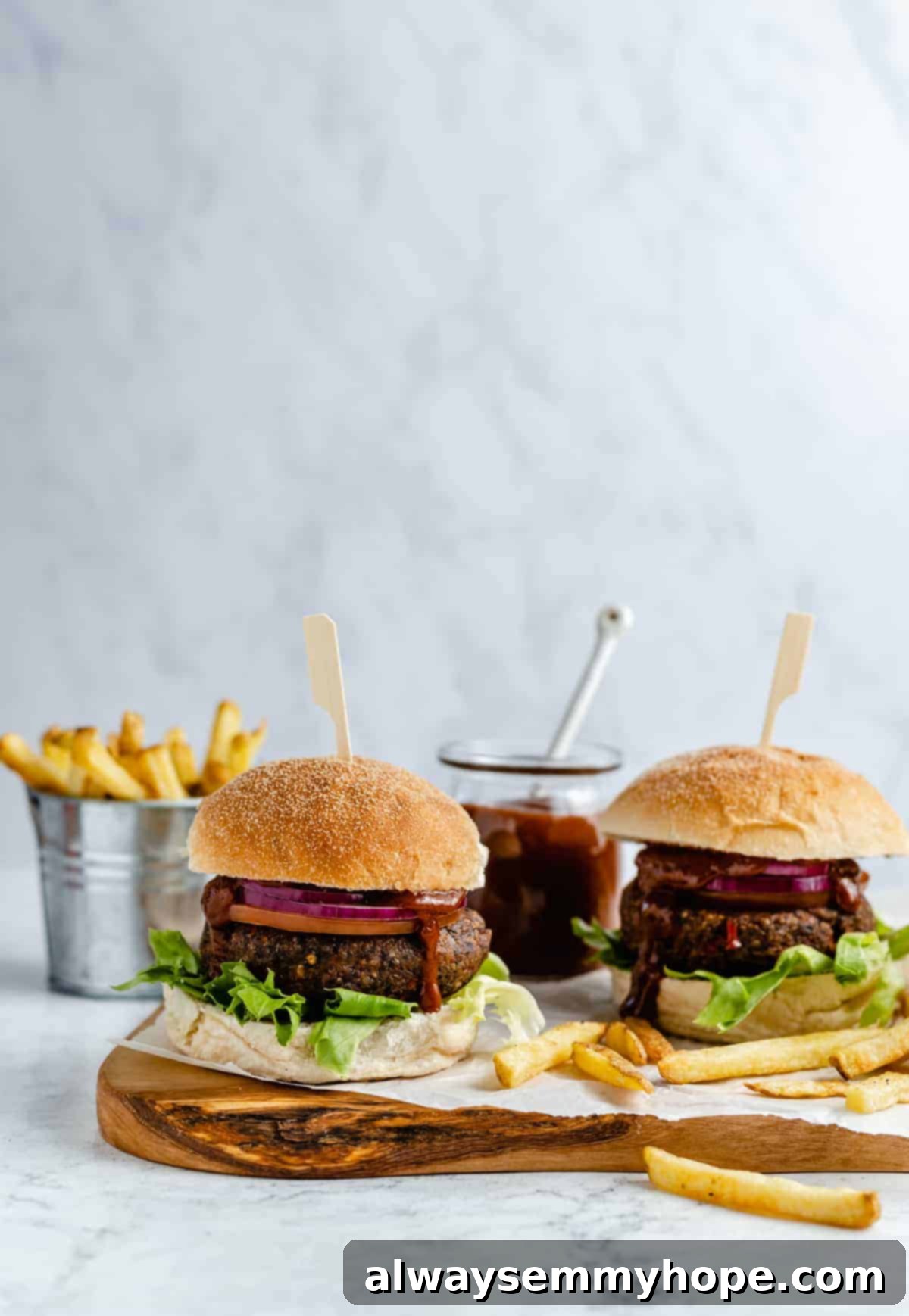 Black bean burgers are made with cooked quinoa, sautéed onions, and smoky strawberry BBQ sauce! Veggie burgers have never tasted this good! Two black bean burgers with strawberry BBQ sauce.
