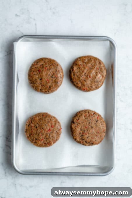 Black bean burgers are made with cooked quinoa, sautéed onions, and smoky strawberry BBQ sauce! Veggie burgers have never tasted this good! Black bean burger patties on a baking sheet.