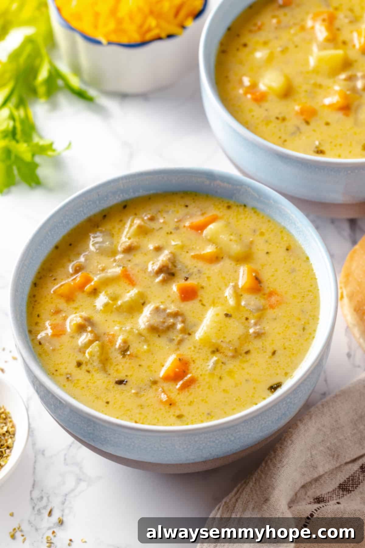 Hearty vegan cheeseburger soup is the ultimate comfort food meal, brimming with savory plant-based flavor and cheesy goodness. It’s like a burger in a bowl! Two bowls of cheesy vegan cheeseburger soup garnished with fresh parsley