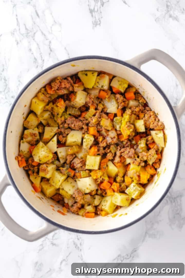 Hearty vegan cheeseburger soup is the ultimate comfort food meal, brimming with savory plant-based flavor and cheesy goodness. It’s like a burger in a bowl! Overhead view of cheeseburger soup ingredients after adding potatoes and spices, before adding broth