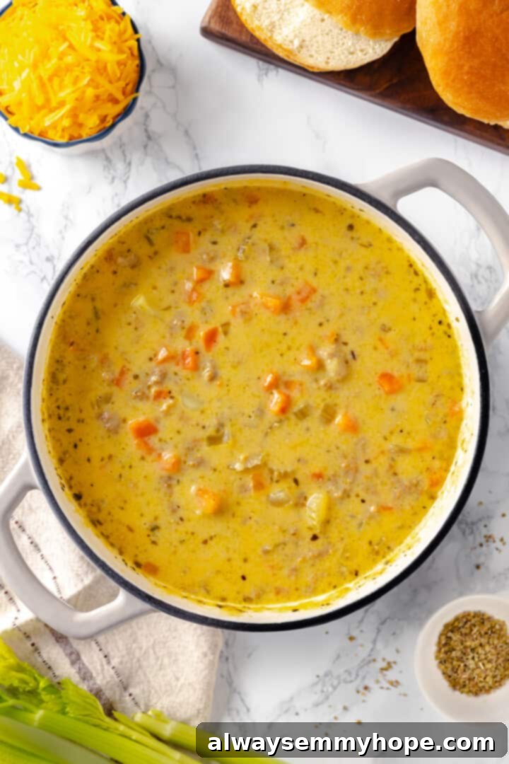 Hearty vegan cheeseburger soup is the ultimate comfort food meal, brimming with savory plant-based flavor and cheesy goodness. It’s like a burger in a bowl! Overhead view of cheeseburger soup in pot with melted vegan cheese, ready to serve