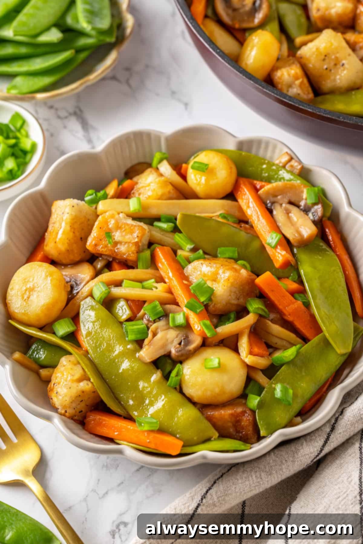 A bowl of vegan moo goo gai pan with chopsticks, ready to eat