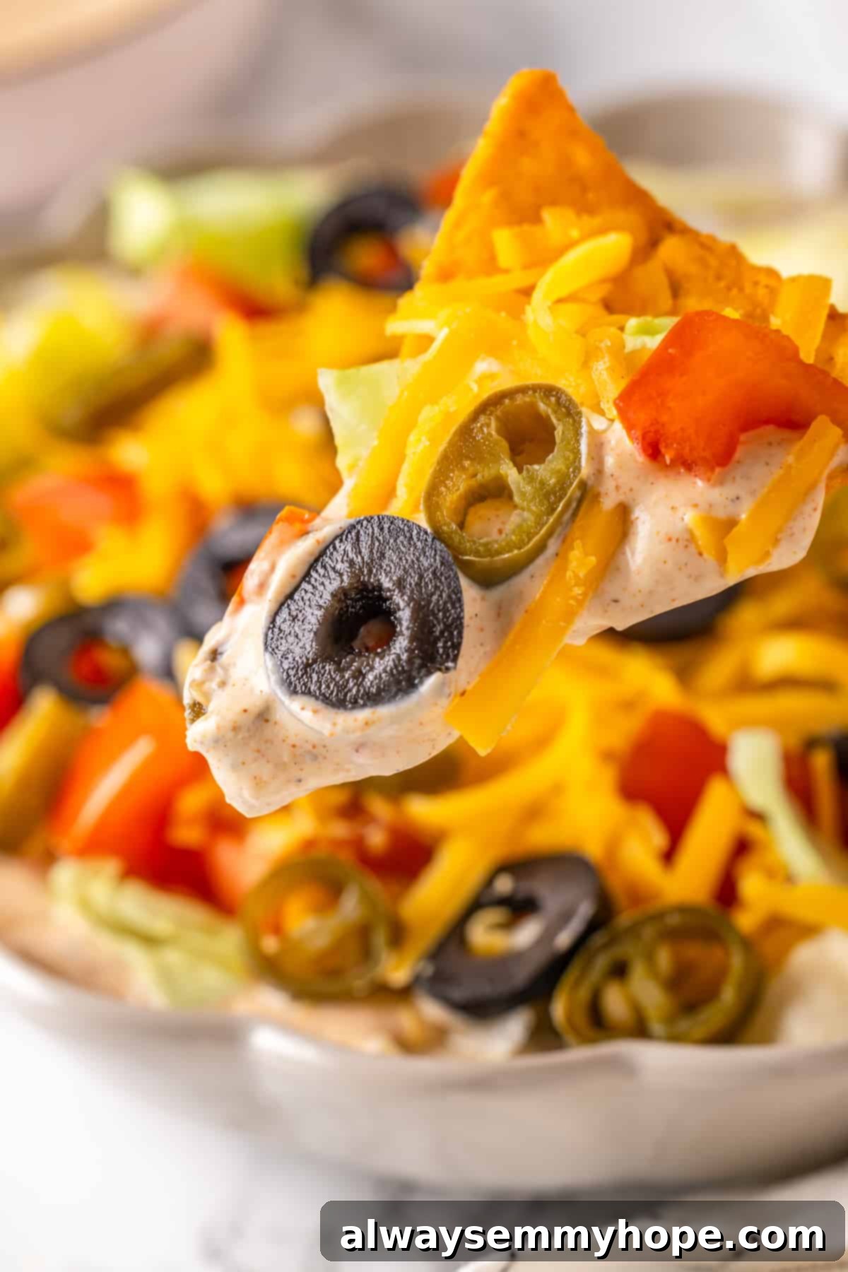 A classic shot of a tortilla chip expertly scooping up a generous amount of the easy vegan taco dip, highlighting its irresistible texture. A crispy tortilla chip expertly scooping up a generous portion of colorful vegan taco dip from a bowl