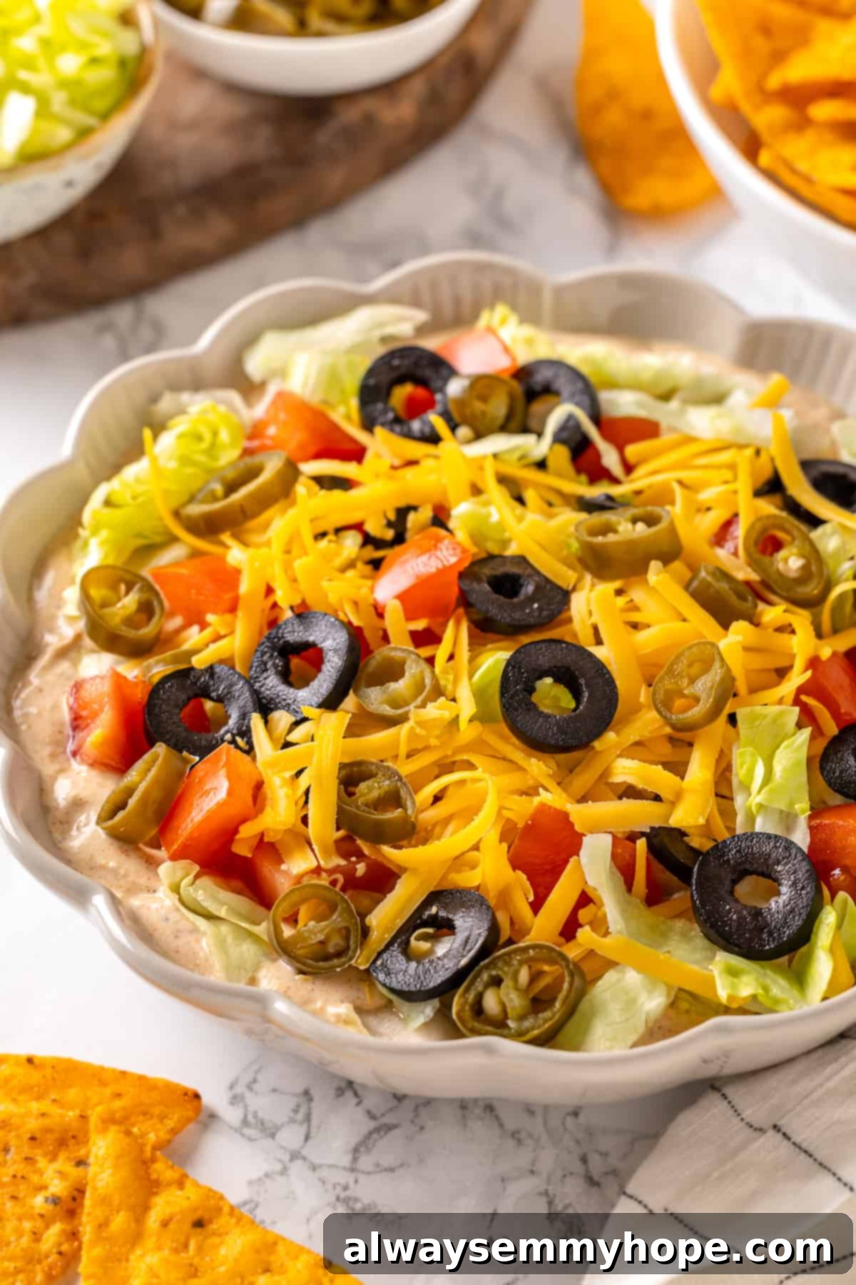 The perfect vegan taco dip, beautifully presented in a serving bowl with all its vibrant toppings, ready to delight your guests. Beautifully presented vegan taco dip in a large serving bowl, garnished and ready for a party