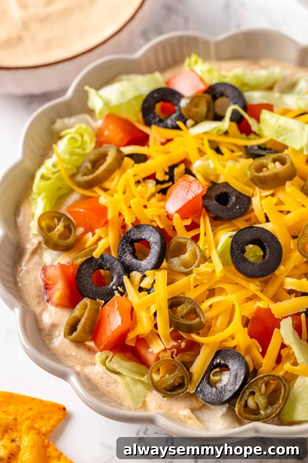 A delicious scoop of vegan taco dip being lifted by a tortilla chip, showcasing its creamy texture and fresh toppings. A tortilla chip scooping up a generous portion of colorful vegan taco dip, ready to be eaten