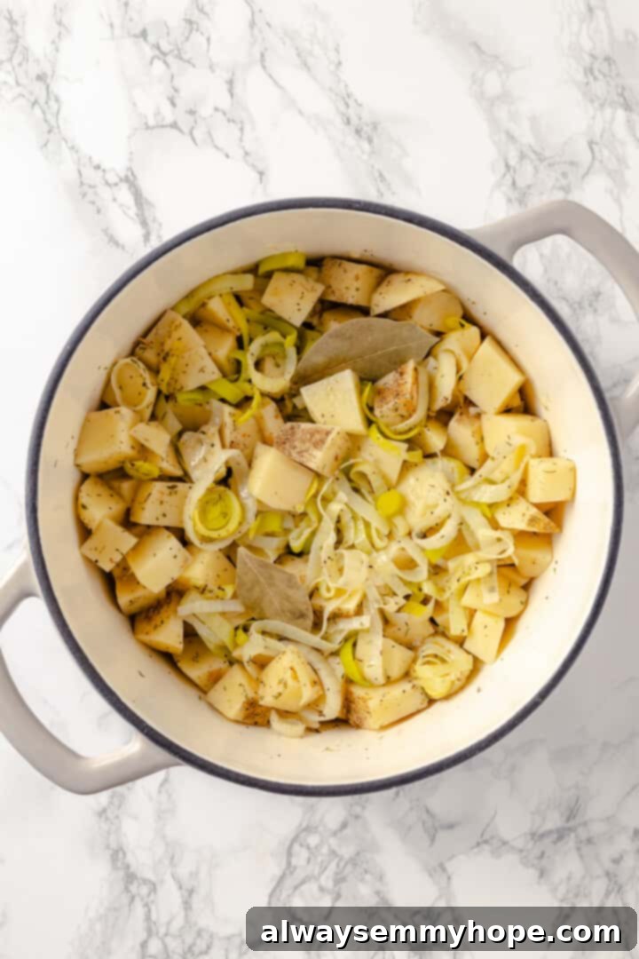 Adding potatoes and spices to the soup base Diced potatoes and seasonings (thyme, marjoram, garlic powder, pepper, bay leaves) added to sautéed leeks and onions in a pot