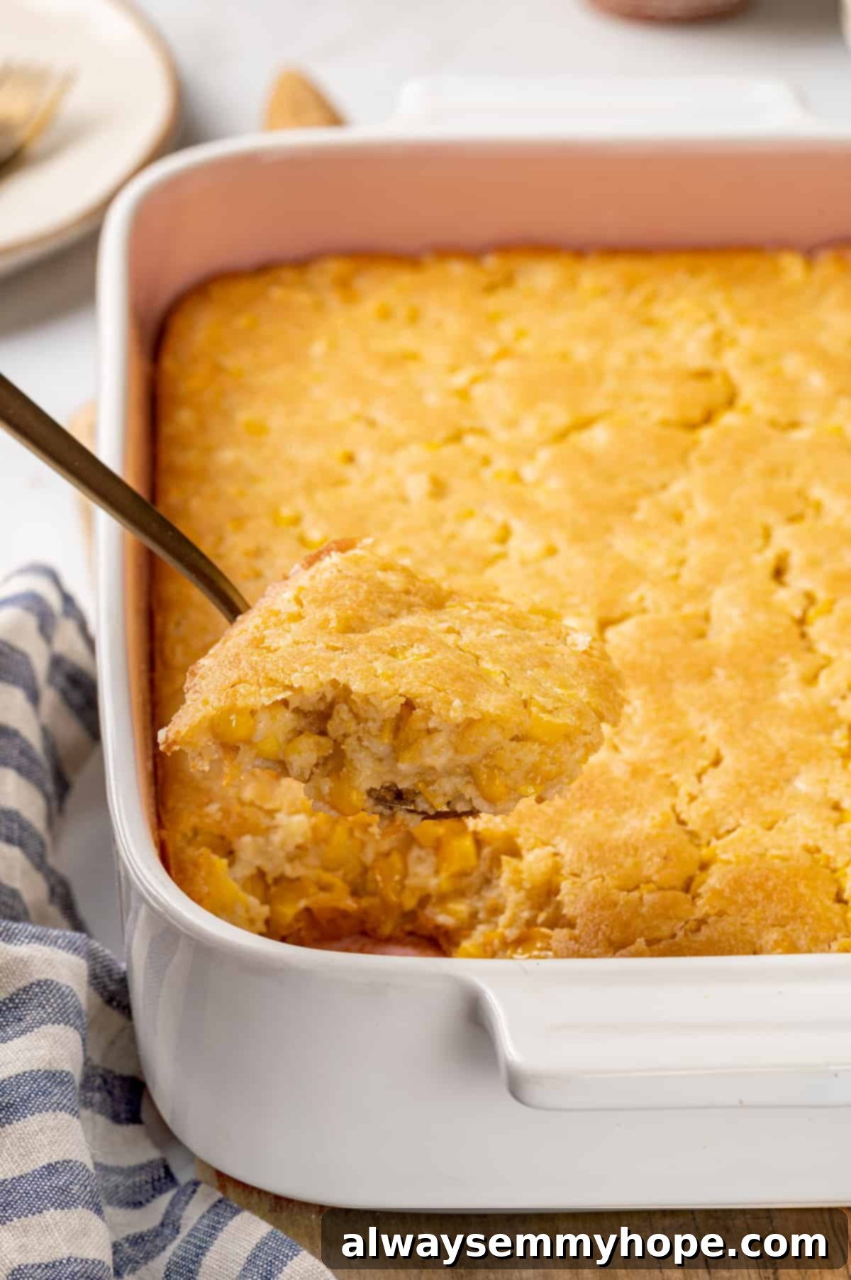 Corn soufflé is a classic holiday side dish, but easy enough to make for a weeknight! You’ll love the sweet flavour and creamy texture. Spoonful of vegan corn souffle in baking dish, showing creamy texture