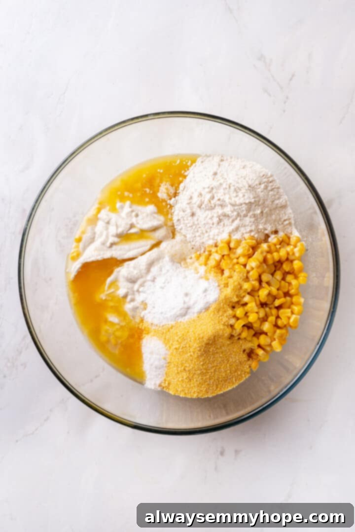Corn soufflé is a classic holiday side dish, but easy enough to make for a weeknight! You’ll love the sweet flavour and creamy texture. Overhead view of all corn soufflé ingredients in a glass mixing bowl before stirring