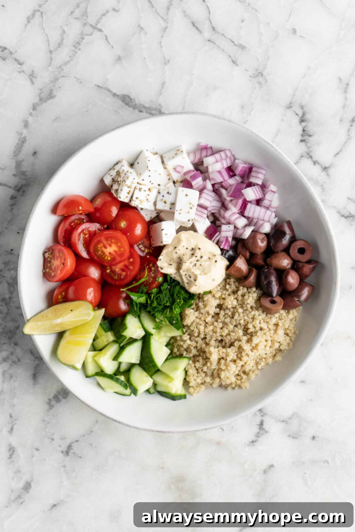 A white bowl filled with a fresh, vibrant cucumber quinoa salad, garnished with herbs