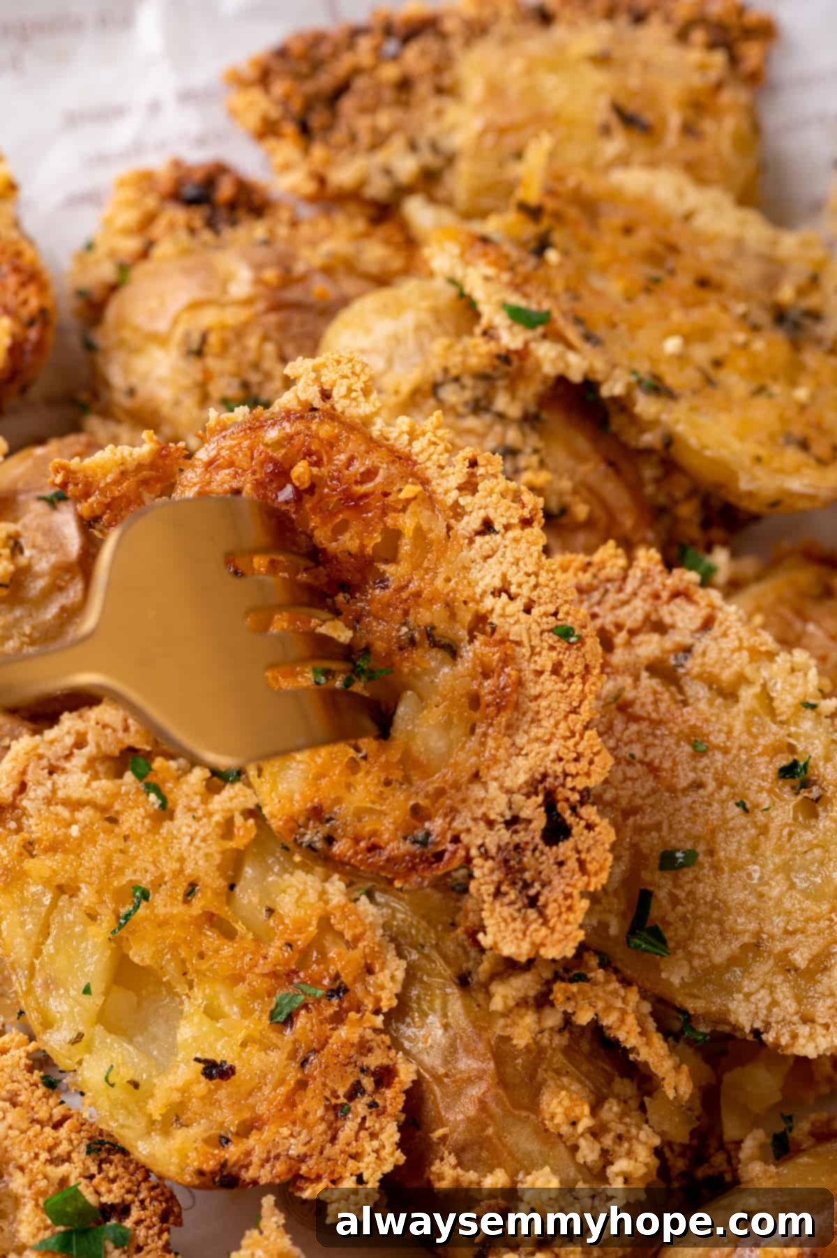 A fork digging into a tender, cheesy vegan Parmesan crusted potato. Fork piercing a crispy Parmesan-crusted potato on a plate